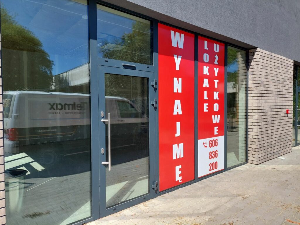 Oklejone witryny lokalu użytkowego reklamą informującą o wynajmie